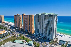 A high-rise hotel with multiple floors, a beach view, and a parking area.
