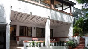 A covered outdoor area with a white wall, a wooden bench, and a small table. - Apartamento Viscaya (Medellin)