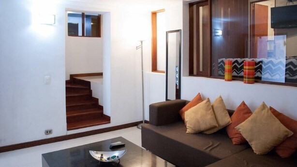 A modern living room with a staircase, a sofa set, and a coffee table. - Apartamento Viscaya (Medellin)
