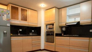 A compact kitchen with wooden cabinets, a built-in oven, and a refrigerator. - Apartamento Viscaya (Medellin)