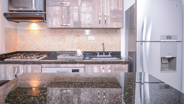 A modern kitchen with a stainless steel refrigerator, microwave, and stove. - Brown Stone Apartments (Medellín)