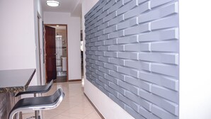 A hallway with a modern design, featuring a grey brick wall and a bar area with two stools. - Brown Stone Apartments (Medellín)