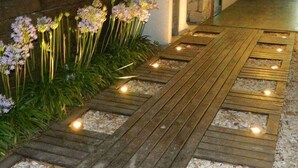 A wooden pathway with embedded lights and a flower bed on the left. - Le Cuyen Aparts (Mar de Las Pampas)