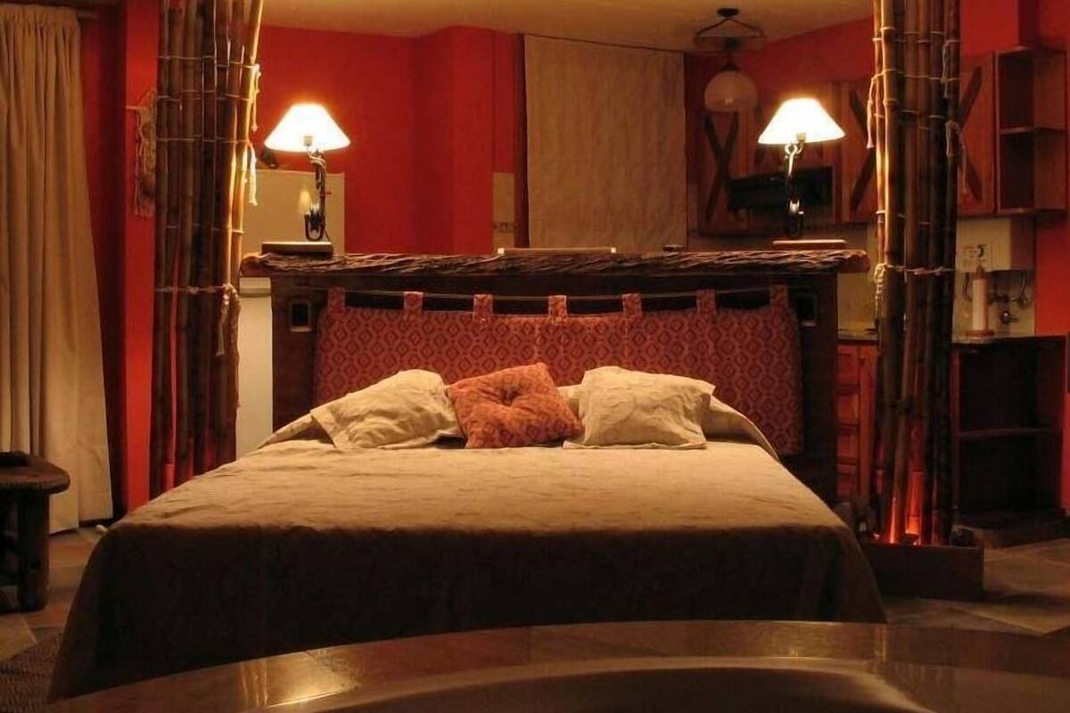 A bed with a wooden headboard, two bedside lamps, and a patterned wall.