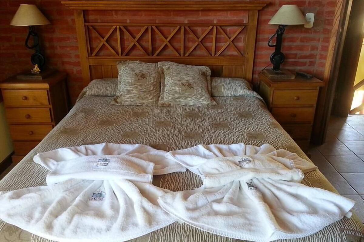 A bed with a wooden headboard, two nightstands with lamps, and a pair of towels on the bed.