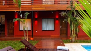 A modern building with a wooden facade, a pool, and a lounge area with a chair and a towel. - Costa Iguazú Apart Hotel (Puerto Iguazú)