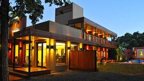 A modern two-story building with a flat roof, large glass windows, and a wooden deck. - Costa Iguazú Apart Hotel (Puerto Iguazú)