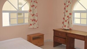 Un dormitorio con una cama, un escritorio de madera y una mesita de noche.