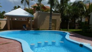 Una piscina con borde curvo, rodeada por un patio de ladrillo.