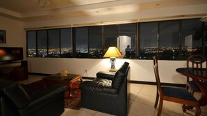 Ein Wohnzimmer mit großem Fenster, einer Couch, einem Tisch und einer Lampe.