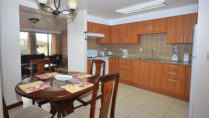 Una cocina compacta con armarios de madera, una mesa de comedor con sillas y un horno empotrado.