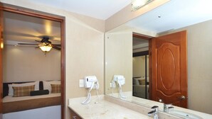 Un baño de hotel con un espejo grande, un lavamanos y dos secadores de pelo montados en la pared.