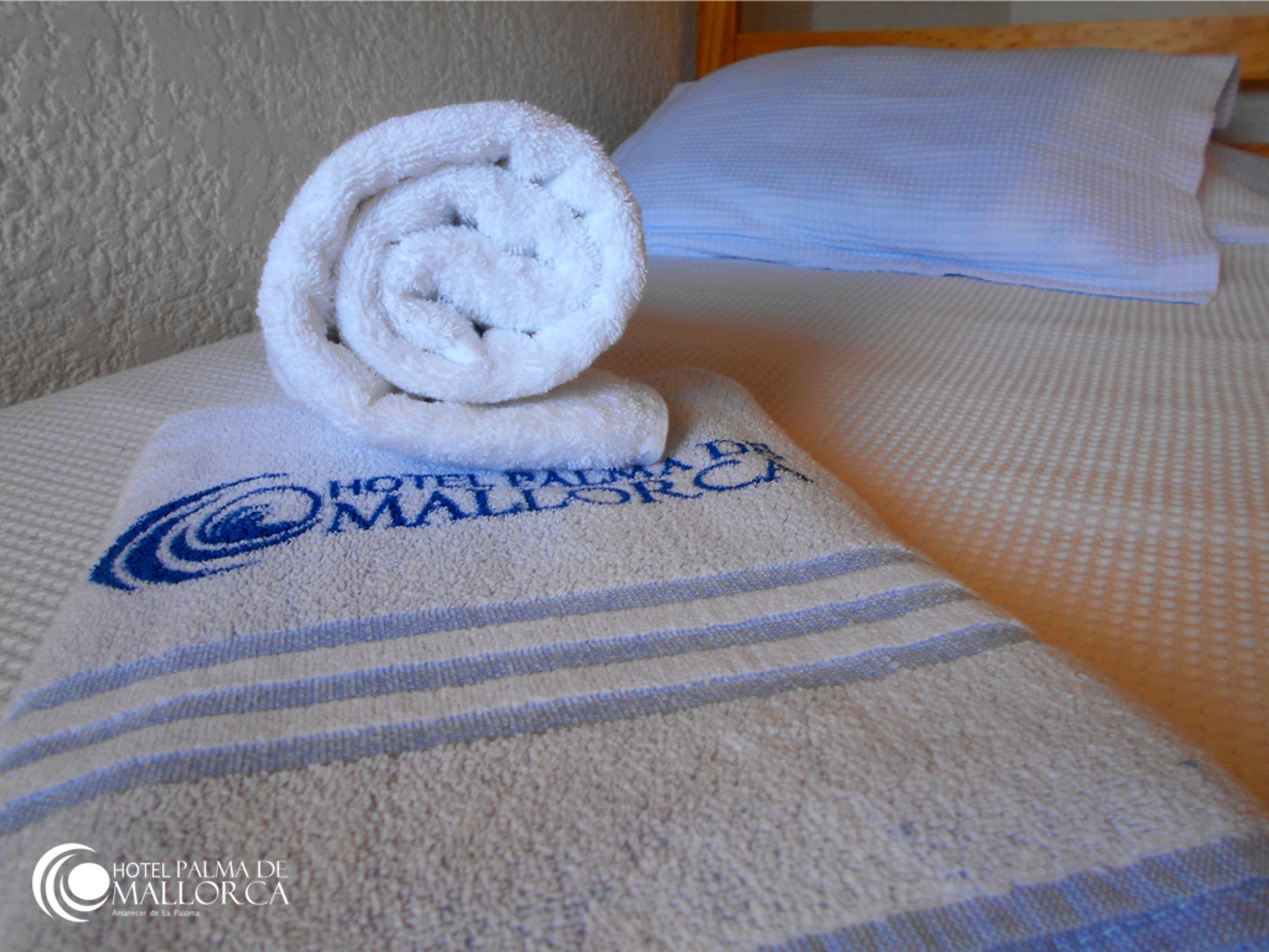 Una toalla doblada con un logotipo y texto sobre una cama.