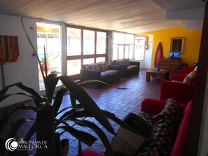 A hotel lobby with a seating area, a television, and a fire extinguisher.