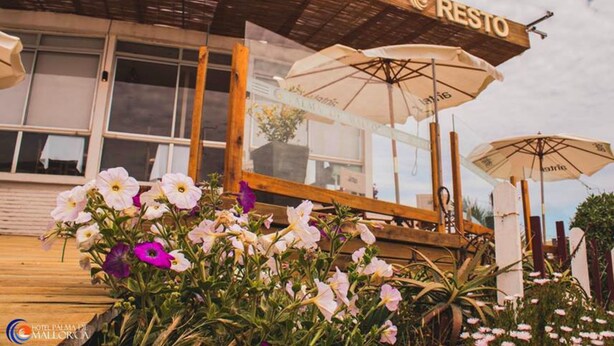 Un restaurant appelé RESTO, doté de parasols sur sa terrasse et d’une façade en bois.