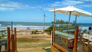 Une terrasse en bois mène à un restaurant situé en bord de mer, doté d’une terrasse et offrant une vue sur l’océan.