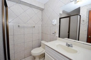 Un baño con inodoro, lavamanos y zona de ducha.