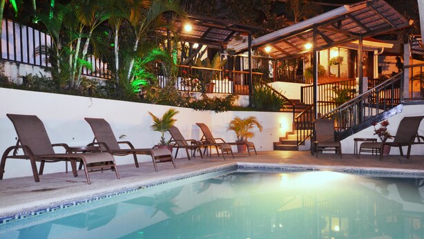 Un espace aménagé au bord de la piscine, avec des chaises longues et un escalier menant à un niveau supérieur.