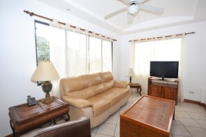 Una sala de estar con un sofá, una mesa de centro, un televisor y un ventilador de techo.