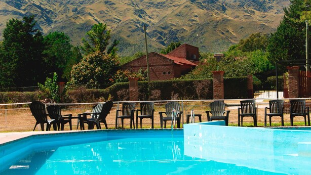 A swimming pool with chairs and a mountain backdrop.