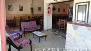 A hotel lobby with seating, a reception desk, and a visible door leading to another area. - Hotel Atlantico Costanera (Santa Teresita)