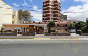 Um edifício de vários andares com um estacionamento à frente.