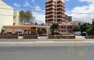 Un edificio de varios pisos con un estacionamiento al frente.