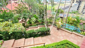 Un jardin sur le toit avec une piscine, entouré d’une végétation luxuriante et de palmiers.