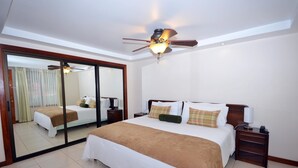 Une chambre d’hôtel avec un grand lit, un ventilateur de plafond, un miroir et une porte-fenêtre coulissante.
