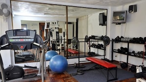Un gimnasio con equipo de ejercicio, cintas de correr, pesas y balones de ejercicio.
