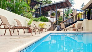 A swimming pool with lounge chairs, a covered seating area, and a staircase leading to a second level. - Casa Reflejos Apartamento 9 (Escazu)