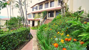 A multi-story building with a garden area featuring various plants and flowers. - Casa Reflejos Apartamento 9 (Escazu)