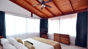 A spacious bedroom with a large bed, a TV, and a ceiling fan. - Casa Reflejos Apartamento 9 (Escazu)