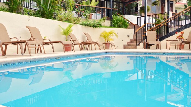 Una piscina con sillas de descanso y plantas en macetas a lo largo del borde.