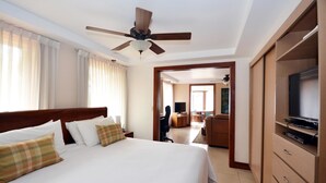 Una habitación de hotel con una cama grande, un ventilador de techo, un televisor y un armario de madera.