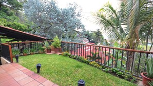 Un patio con suelo de baldosas, cerca de metal y diversas plantas en macetas.