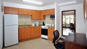 Una cocina con armarios de madera, un refrigerador blanco, una estufa, un microondas y una cafetera.