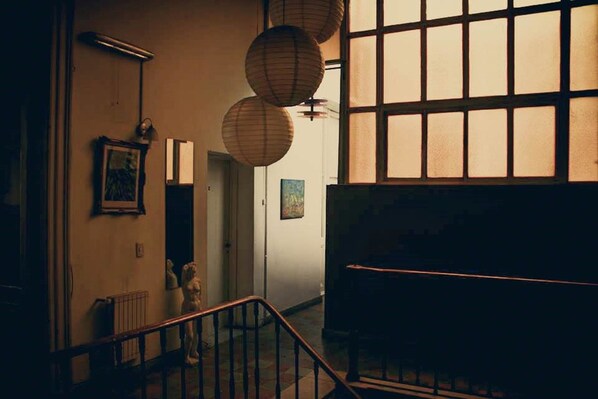 A staircase with a wooden handrail leading to a landing. There are hanging paper lanterns above the staircase.