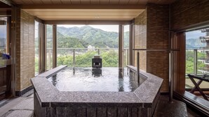 Een hottub met uitzicht op bergen, een houten bankje en een glazen deur.