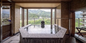 Ein Whirlpool mit Blick auf Berge, eine Holzbank und eine Glastür.