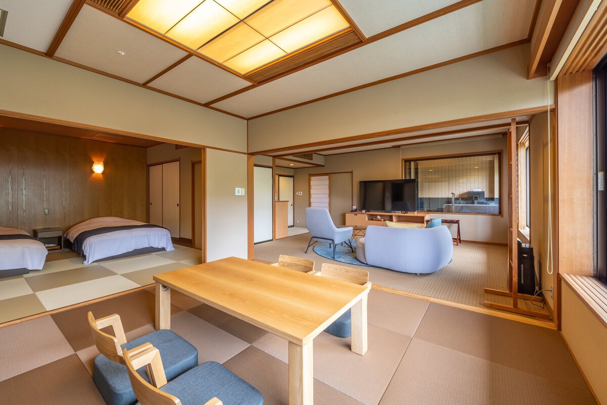Een traditionele Japanse kamer met tatami vloerbedekking, een lage houten tafel en een bank.