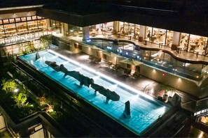 Ein Poolbereich auf dem Dach mit Sitzgelegenheiten und Blick auf das Restaurant darunter.