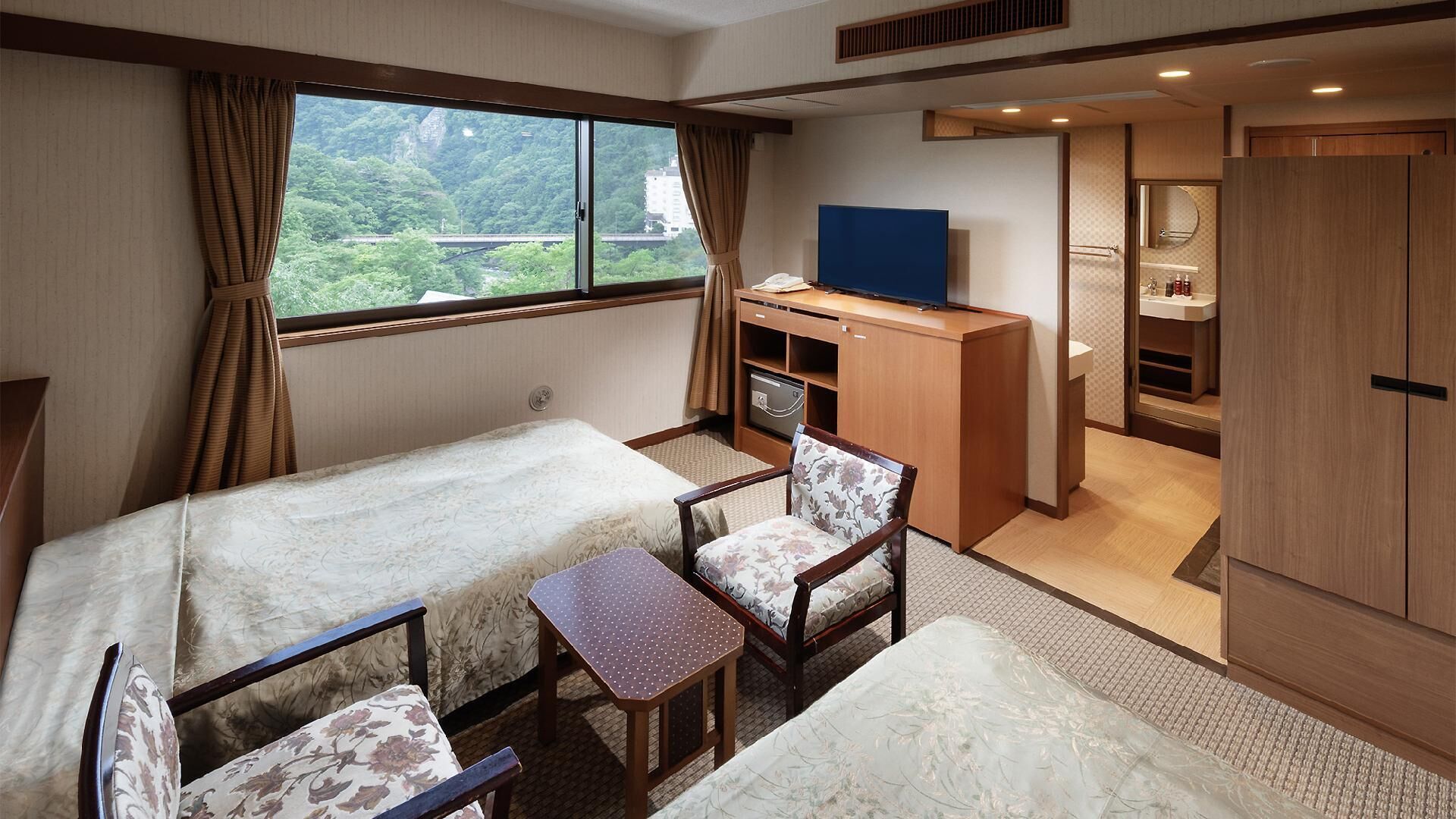 Ein Zimmer mit Bett, Schreibtisch, Stuhl, Fernseher und Bad.