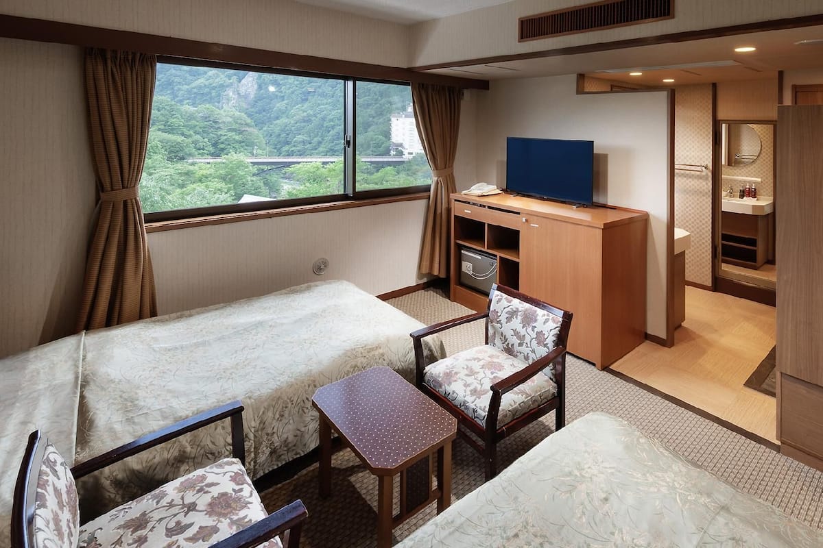 Een kamer met een bed, een bureau, een stoel, een televisie en een badkamer.