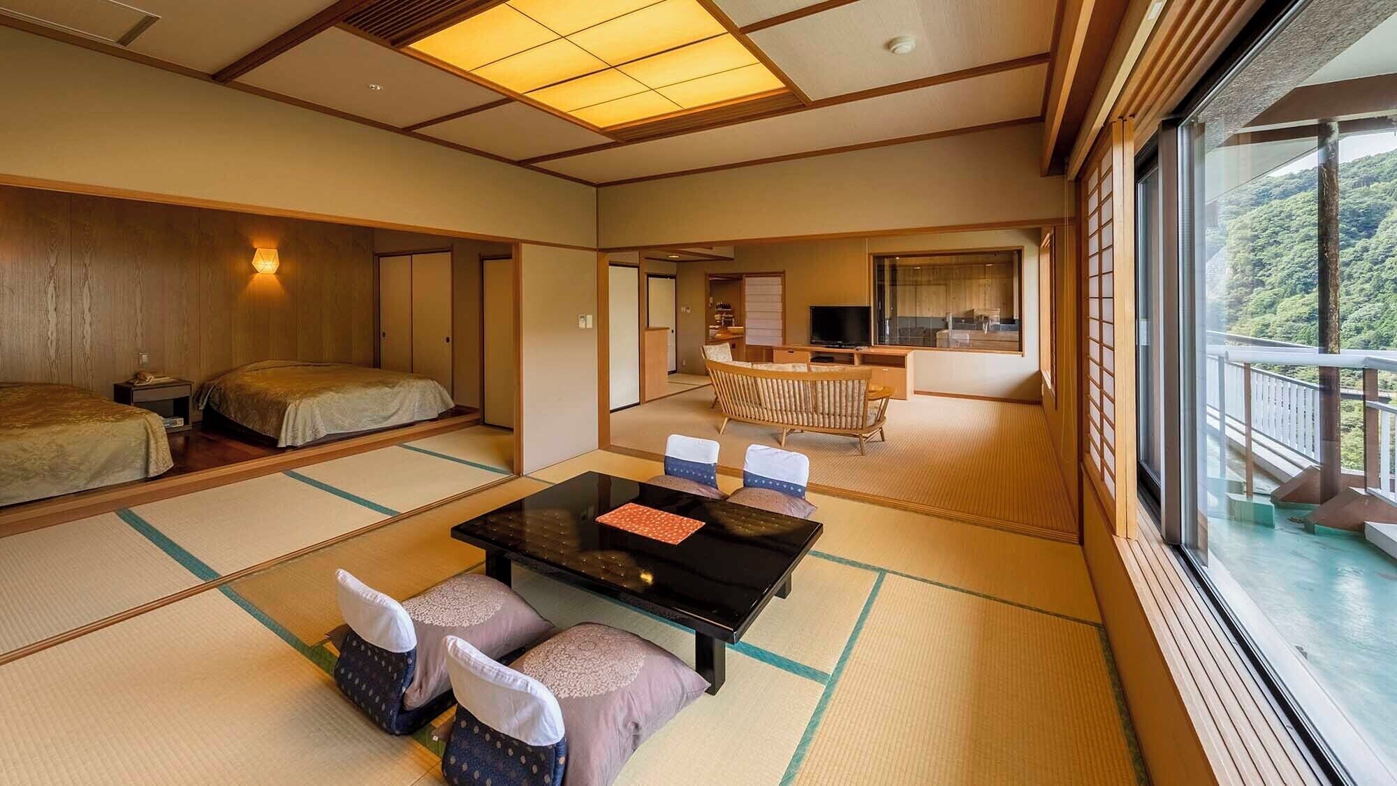 Ein traditioneller japanischer Raum mit Tatami-Boden, einem niedrigen Tisch mit Kissen, einer Couch und Blick auf einen üppigen Wald.