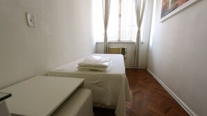 Una habitación pequeña y limpia con una cama individual, una mesa y una silla.