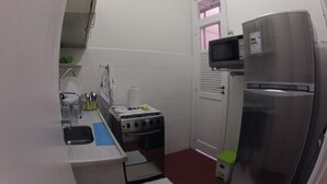 Una cocina compacta con un refrigerador de acero inoxidable, un microondas, una estufa y un lavamanos.