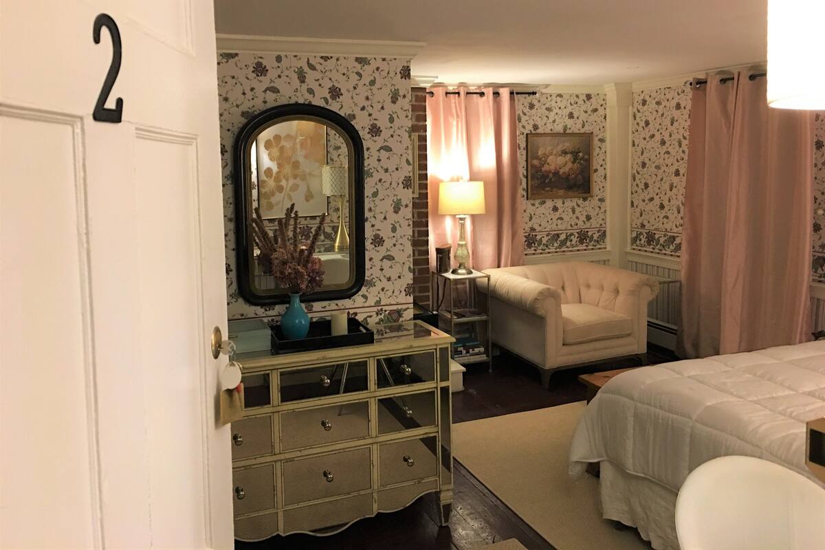 A bedroom with a bed, a dresser, a chair, a lamp, and a mirror.