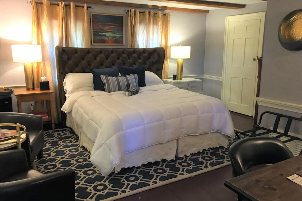 A hotel room with a large bed, two bedside tables, a desk, and a chair.