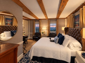 A hotel room with a large bed, a round mirror, a desk, and a view of the outdoors. - Center Lovell Inn (Lovell)